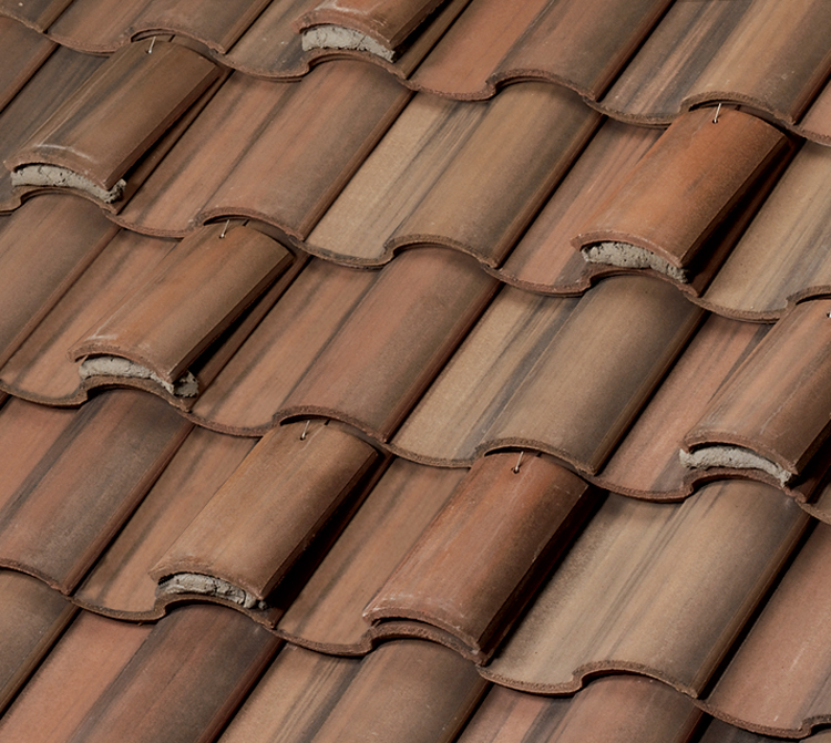 Close-up view of overlapping brown clay roof tiles arranged in neat rows, showing the curved shapes and textured surfaces typical of traditional roofing materials.