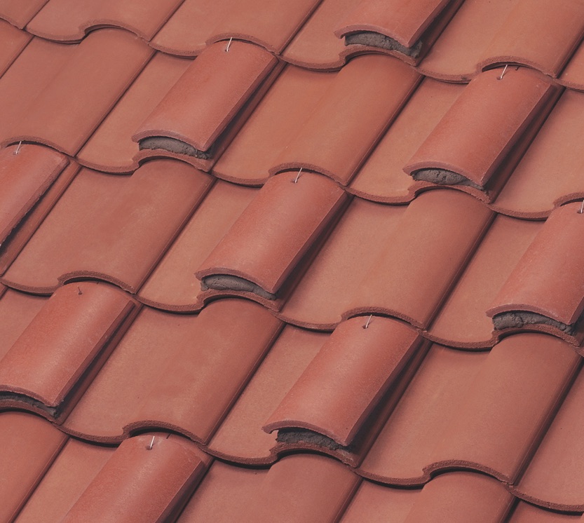 Close-up view of red clay roof tiles arranged in overlapping rows, showing the textured surface and curved shapes typical of traditional tiled roofing.
