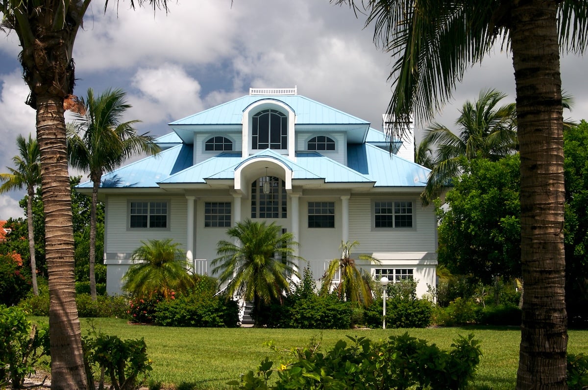 Light blue metal roof on Florida home with palm trees and landscaping