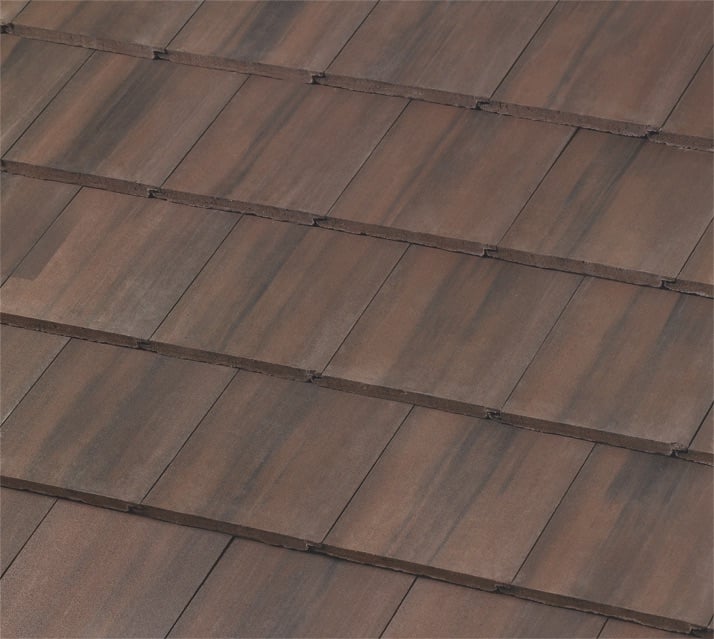 Close-up view of brown, rectangular roof tiles arranged in overlapping horizontal rows, creating a textured and uniform pattern. The tiles have slight color variations for a natural appearance.