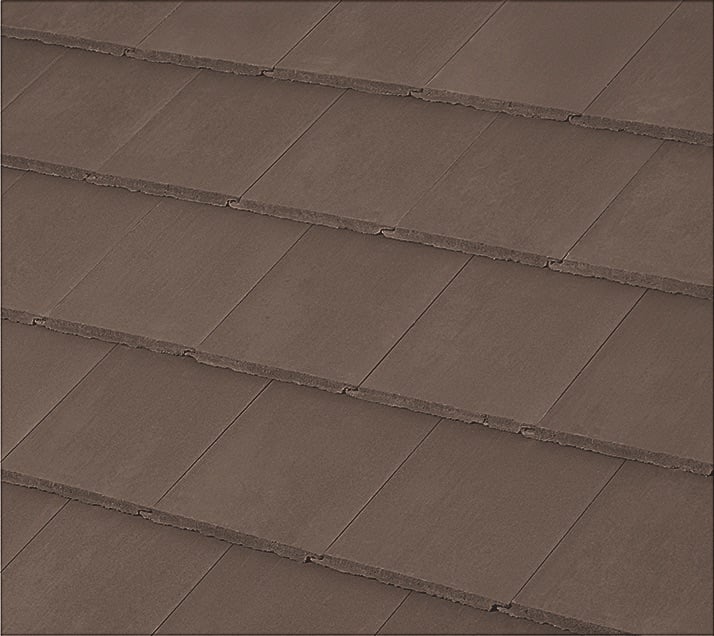 Close-up view of overlapping brown roof shingles arranged in neat, horizontal rows. The shingles have a smooth texture and uniform color, giving the roof a clean and orderly appearance.