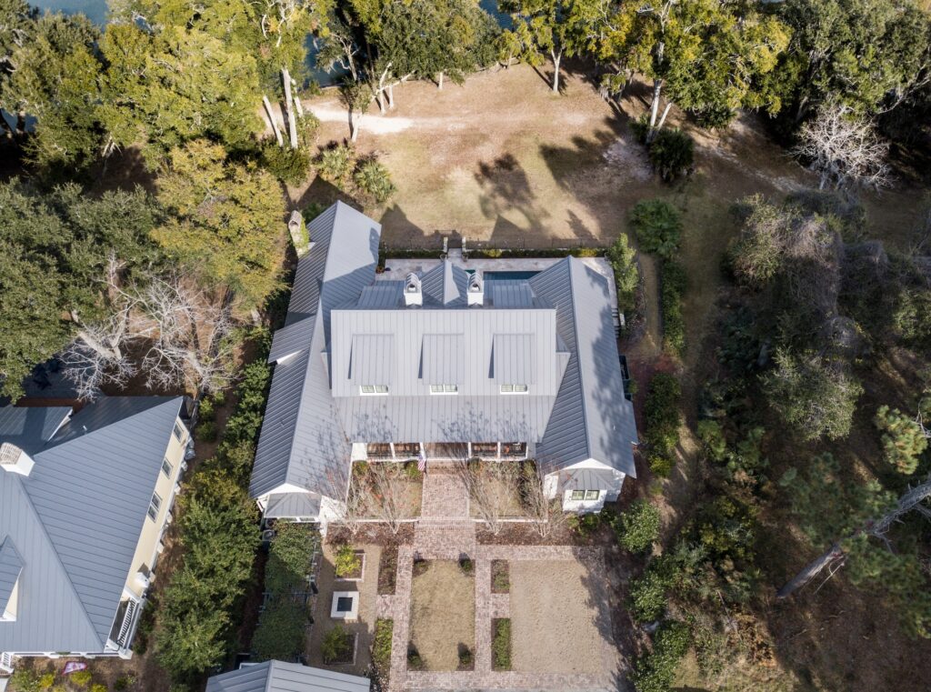 High angle aerial view of expensive house with metal roof on landscaped property.