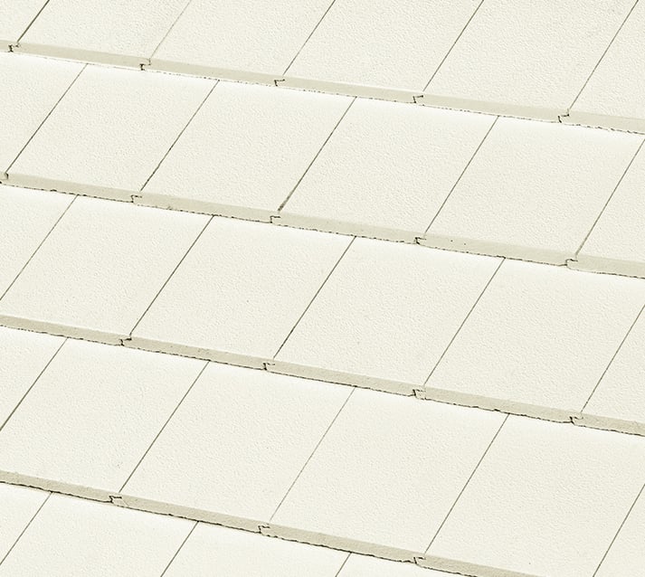 Close-up view of overlapping, rectangular, light-colored roof shingles arranged in neat, horizontal rows.