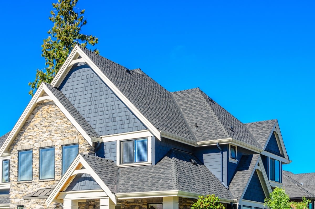 Modern two-story house with gray siding, stone accents, and a dark gray shingle roof