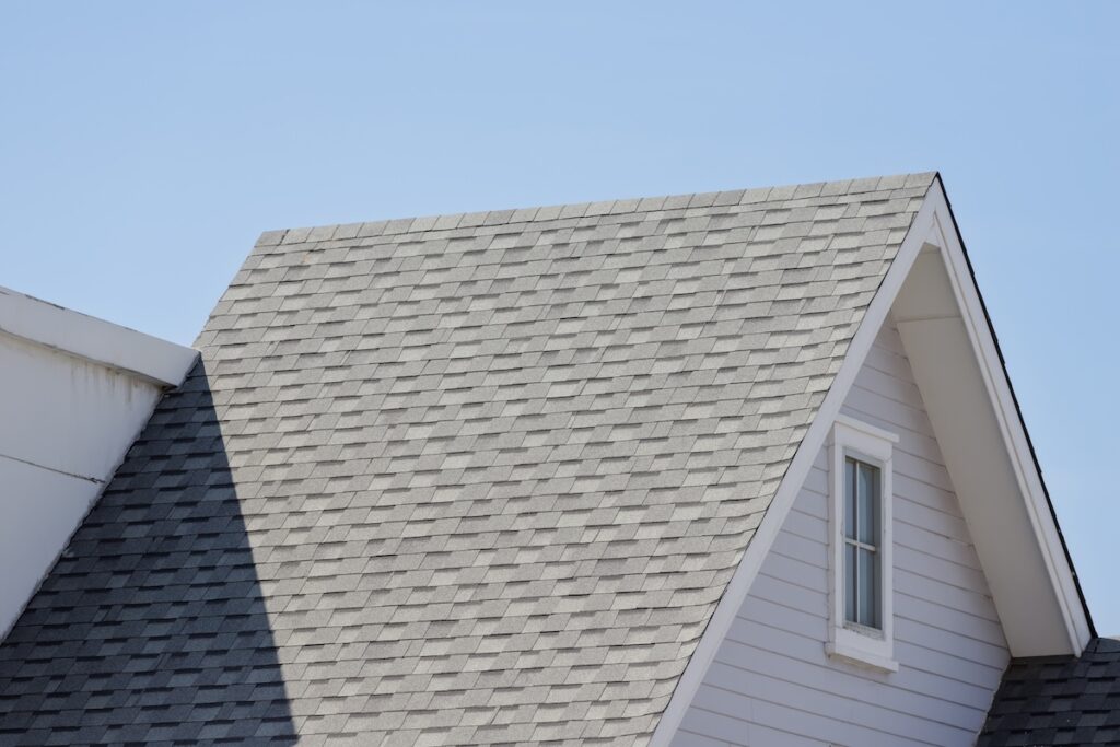The image shows the gray architectural shingle roof of a house with a steep triangular gable.