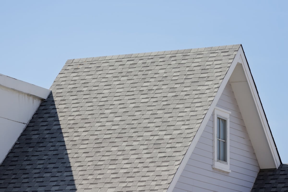 The image shows the gray architectural shingle roof of a house with a steep triangular gable.
