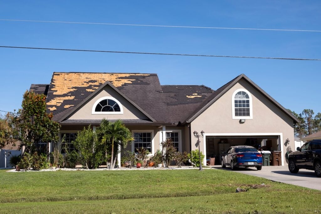 Damaged house roof with missing shingles after hurricane Ian in Florida.