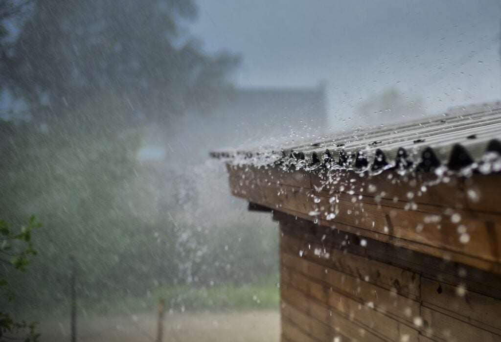 Heavy rain pours down on a wooden roof
