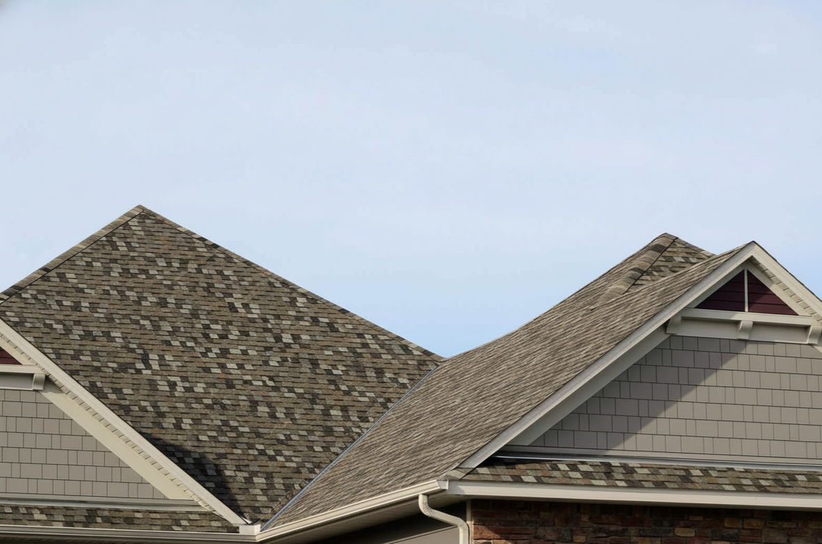 Professional roofing contractors installing a hip roof on a residential home, showing the four-sided slope structure