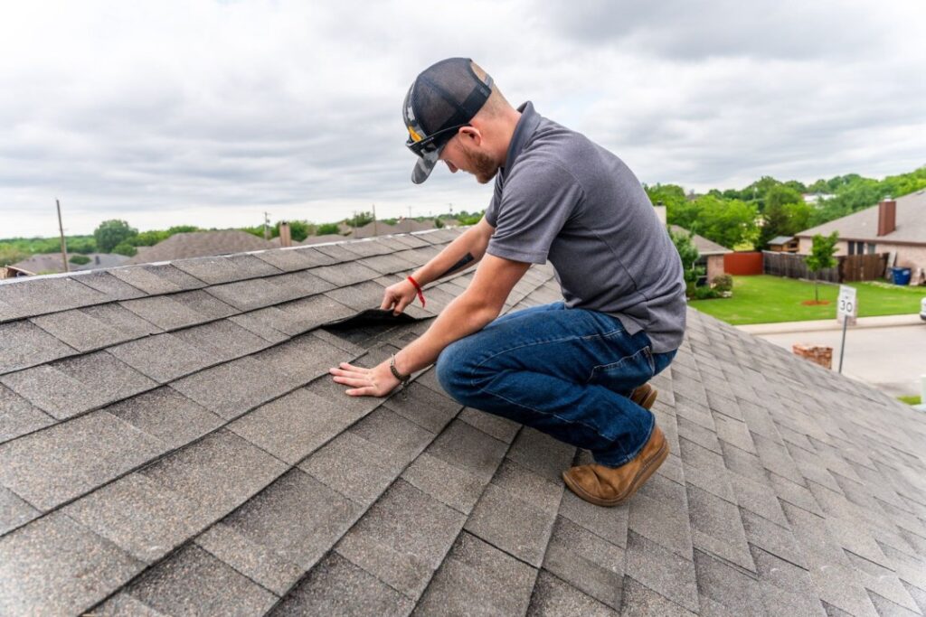 Homeowner and roofing professional inspecting ridge cap shingles on residential roof for maintenance