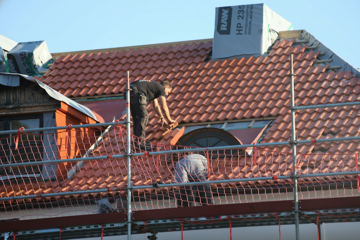 Professional roofing contractors performing storm preparation maintenance on a residential roof