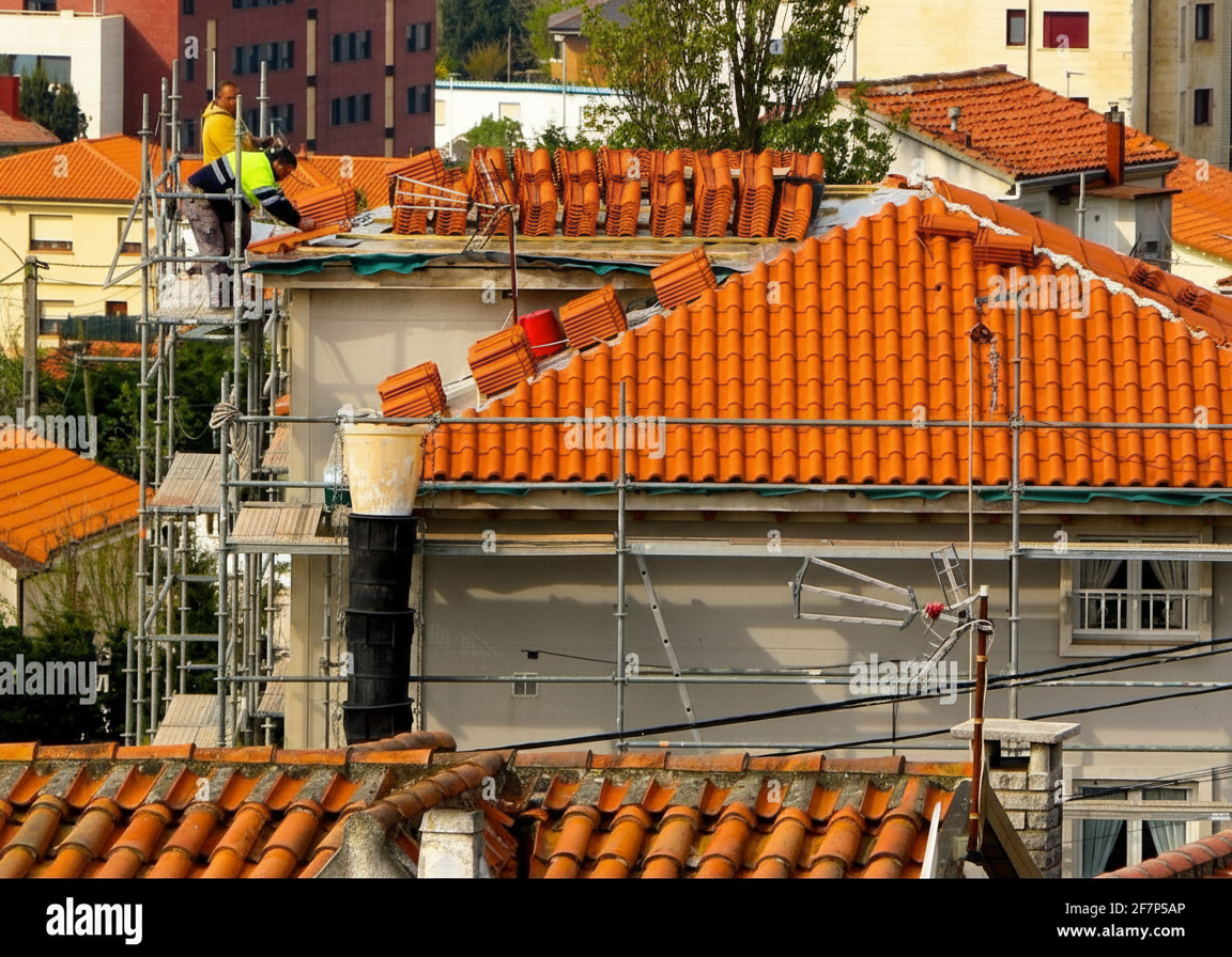 Professional roofers installing Spanish clay tiles on a residential home