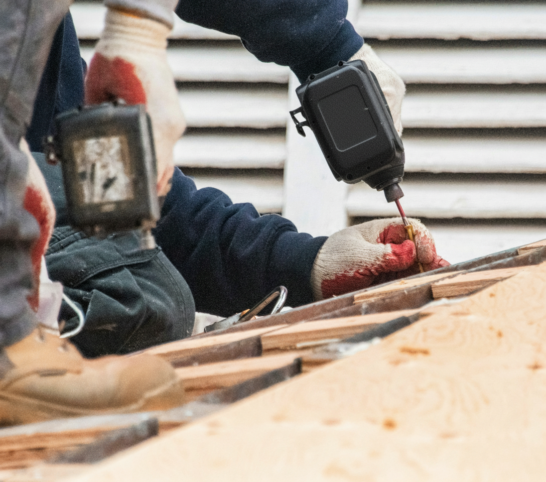 Construction workers installing hurricane straps and reinforcement on residential roof