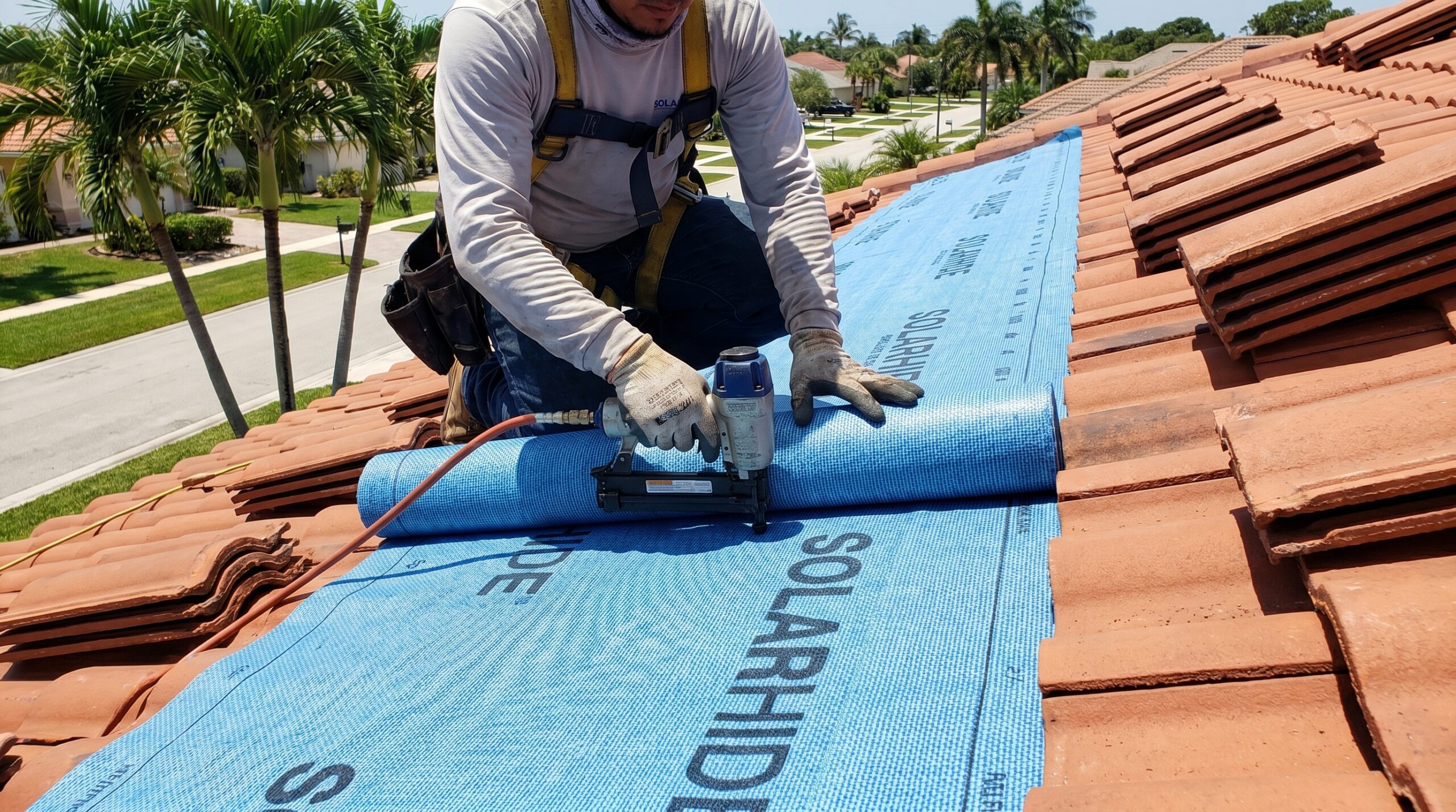 Roofer installing synthetic underlayment on Florida tile roof with proper overlap and fastening